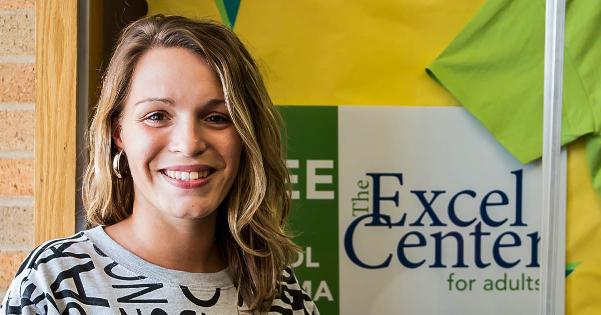 Katie Reigelsperger poses in front of an Excel Center sign