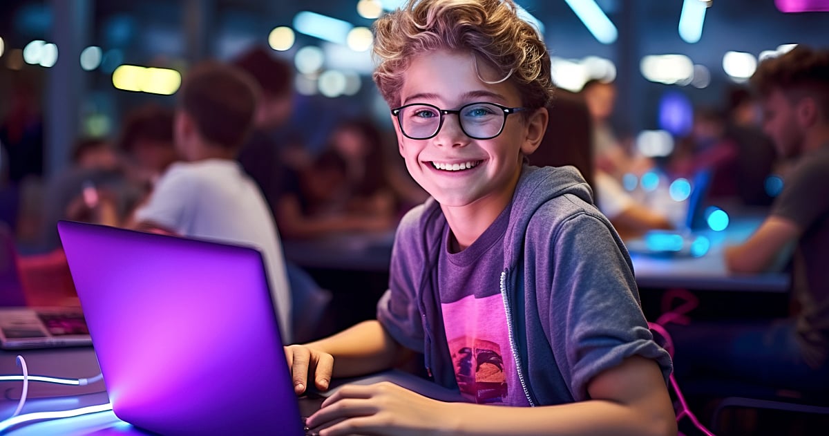 Portrait of smiling boy using laptop in gaming club at night time