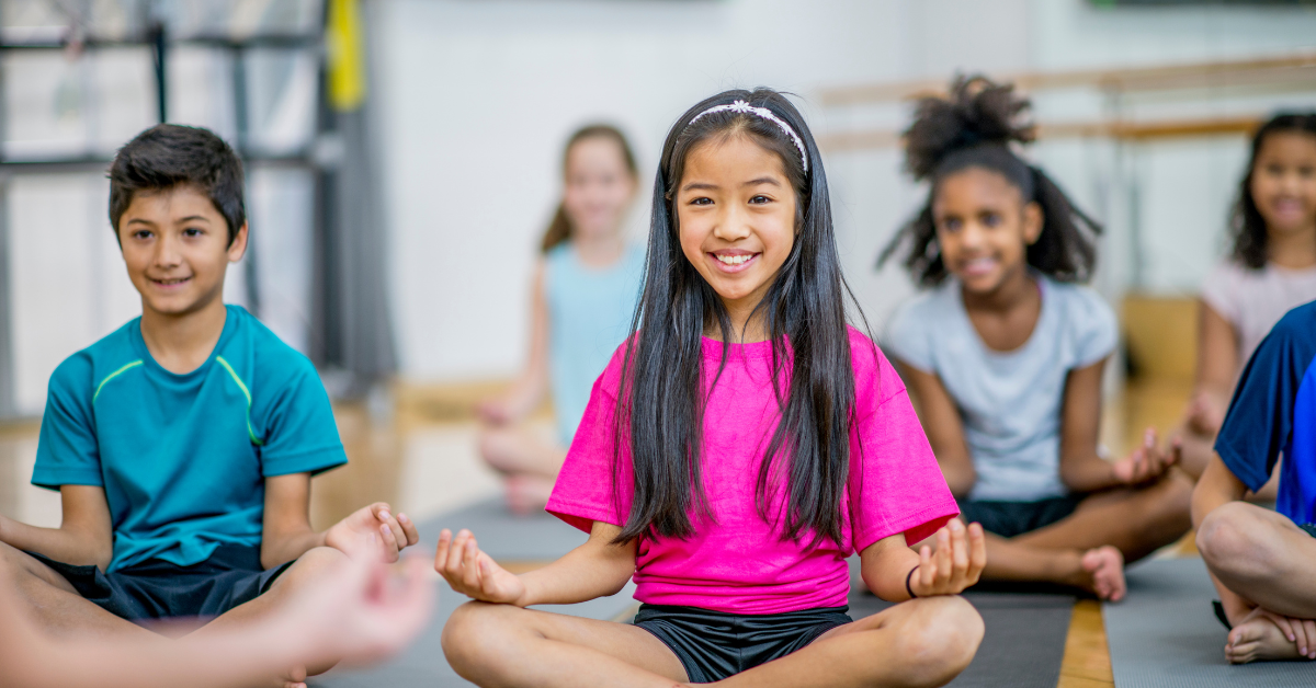 Diverse students smiling while doing yoga at school
