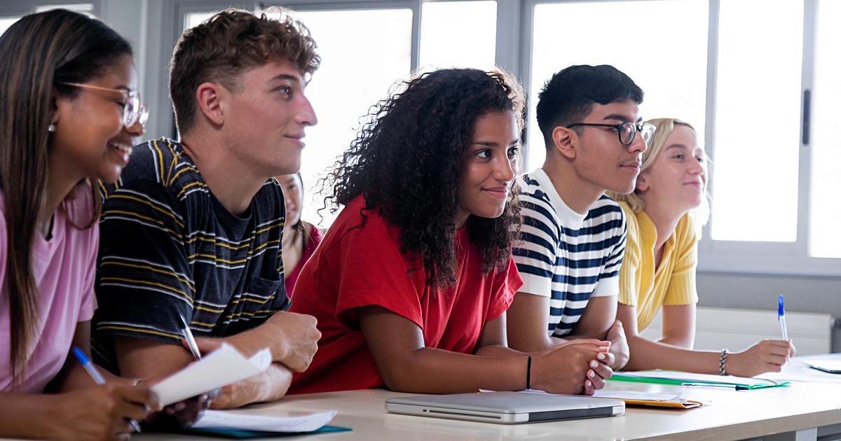 Black female high school student in class with multiracial classmates.