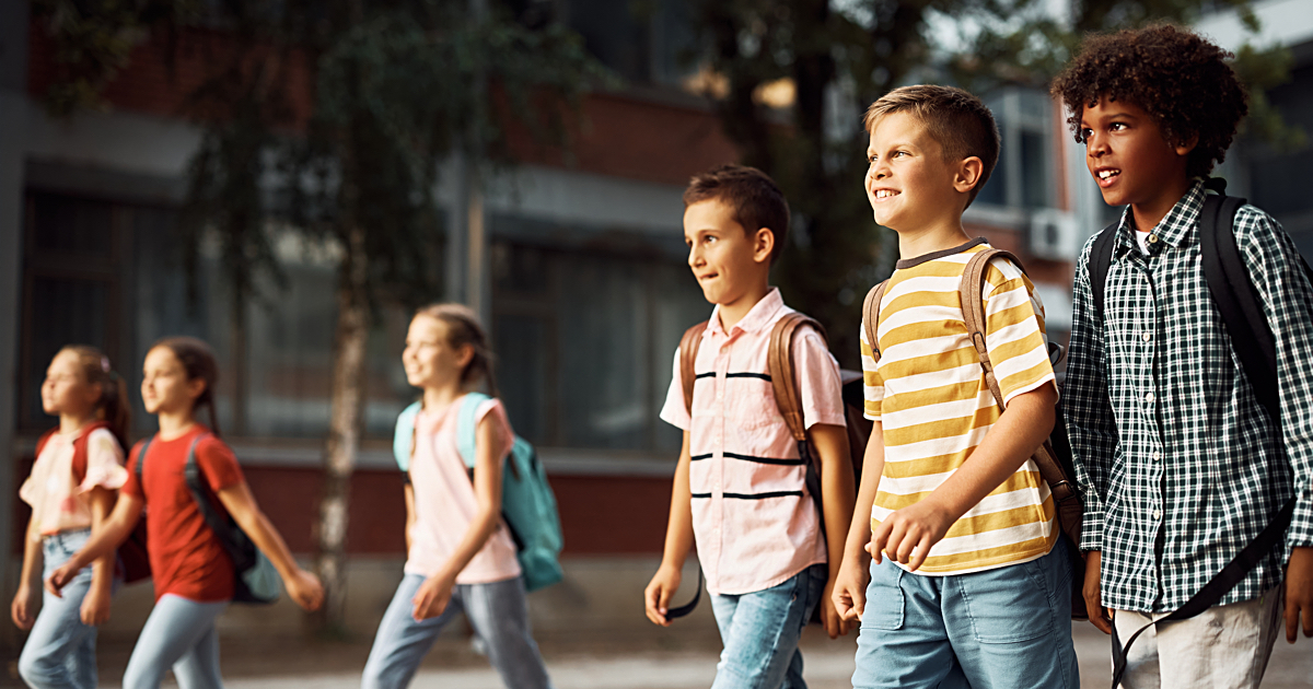 Multiracial group of happy elementary students coming to school.